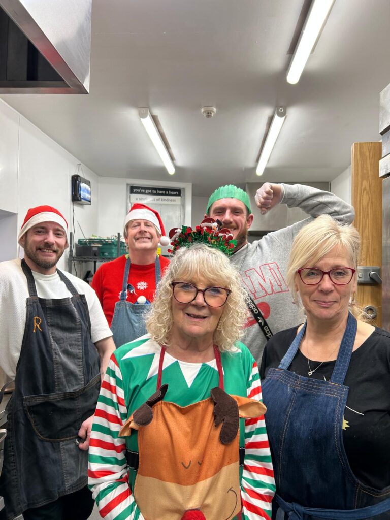 Group of people in a kitchen with Christmas clothes on