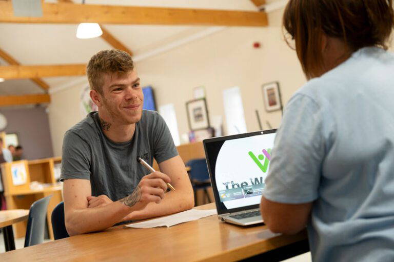 Smiling man with pen in hand speaking to woman