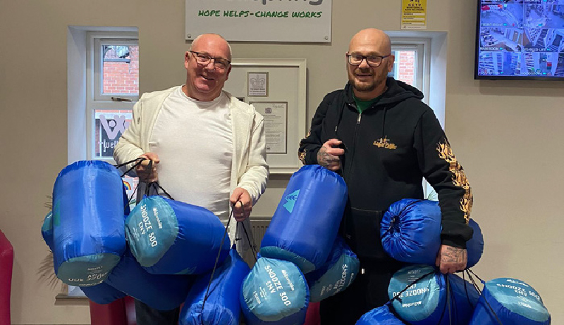 Two men holding sleeping bags