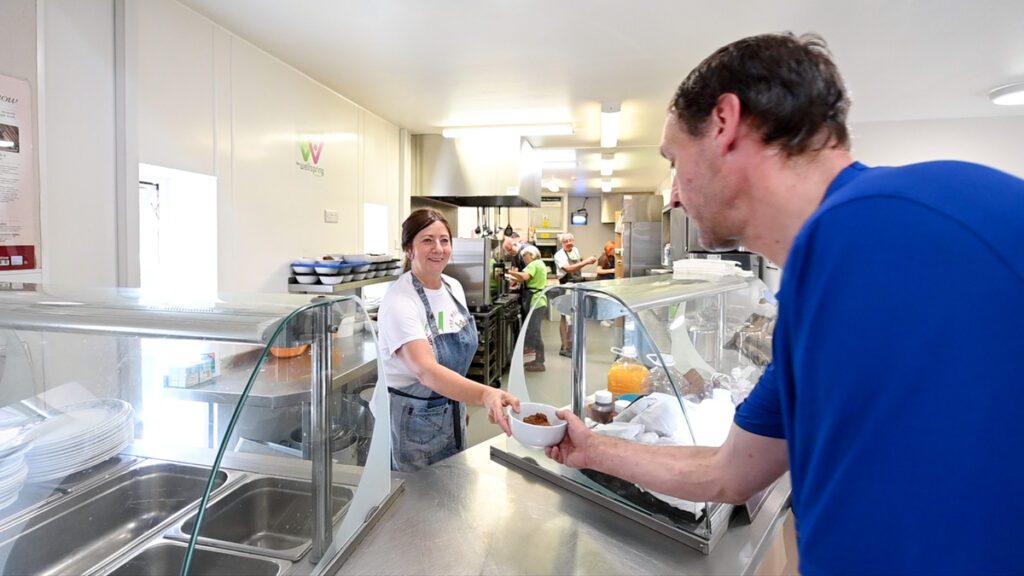 Woman handing a man a bowl of food