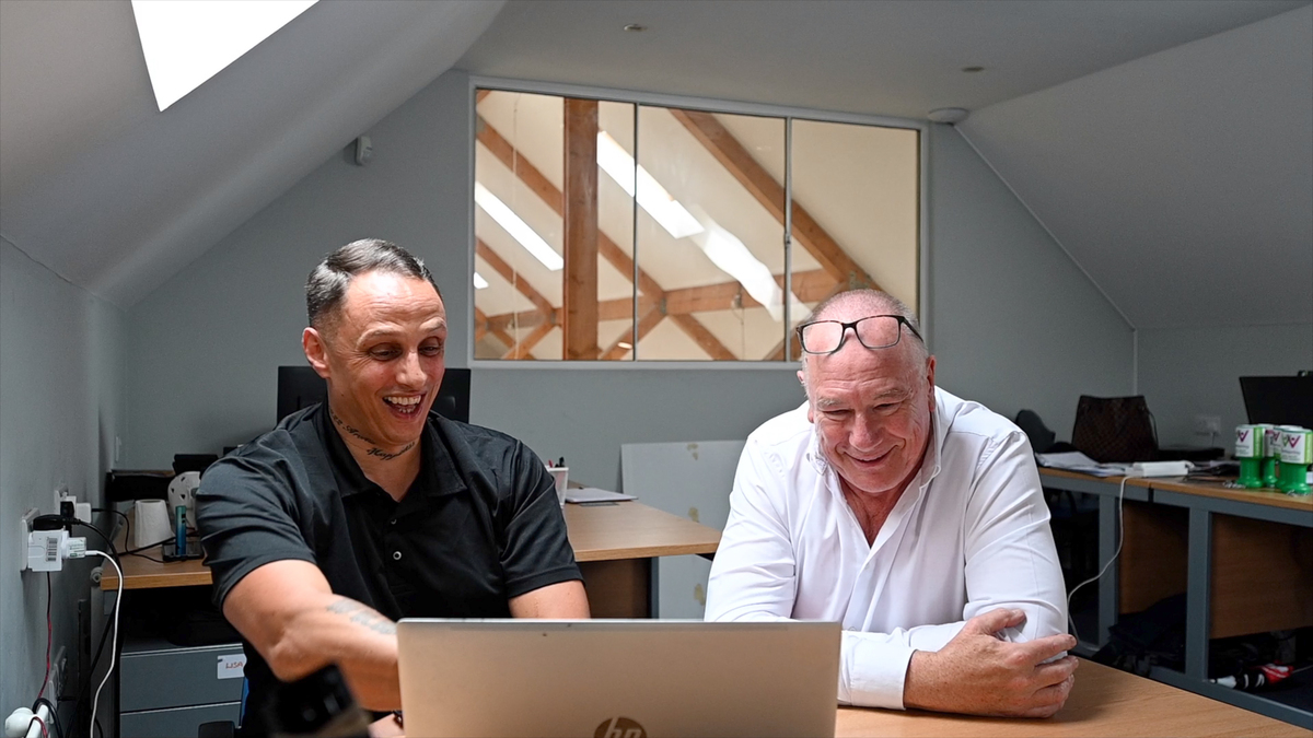 Man laughing and pointing to a computer with another man